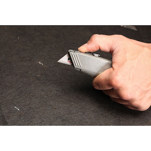 STANLEY 10-789 utility knife held in hand, silver metal body with extended blade, side view.