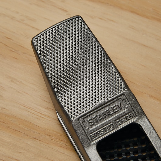 Close-up of STANLEY 21-295 Surform tool with textured metal surface on wood background.