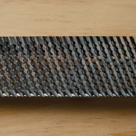 STANLEY 21-295 wood rasp close-up, showing sharp metal teeth and rectangular holes against wood background.