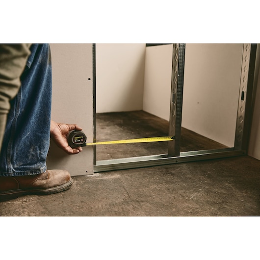 STANLEY 30-085 tape measure used for measuring wall frame on concrete floor, close-up.