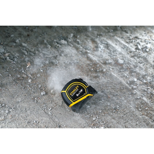 STANLEY 30-615 tape measure, black and yellow, on rough concrete surface, product photography.