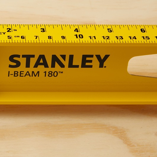 Photo of STANLEY 42-324 I-Beam 180 yellow level tool with imperial and metric scale on wood surface