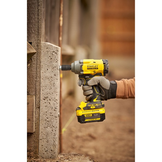 Photo of STANLEY SBW920M2K impact driver being used on concrete, side view, yellow and black tool.