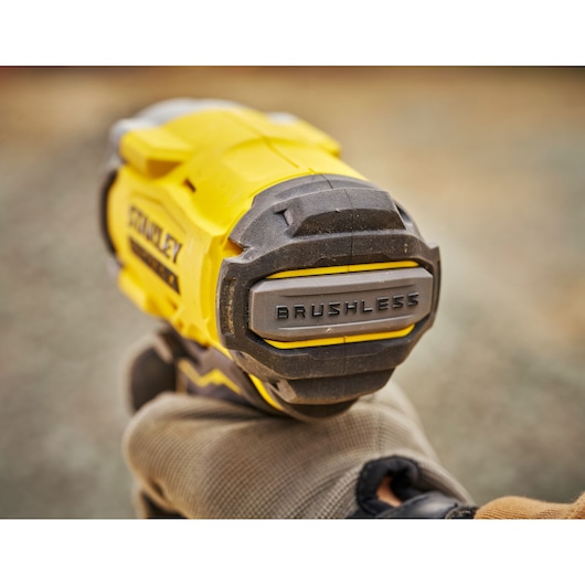 Close-up photo of STANLEY SBW920M2K brushless power tool with yellow and black housing, held by a gloved hand.