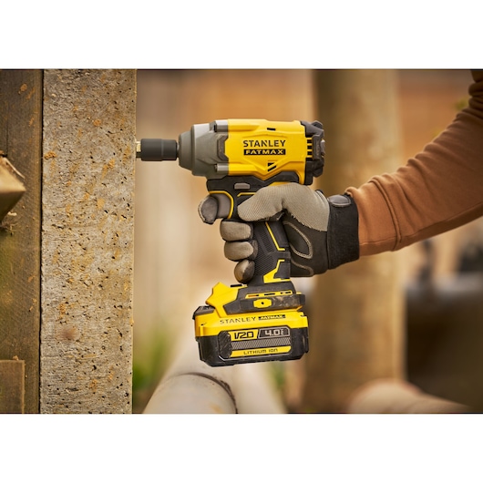 Stanley SBW920 cordless impact driver held in gloved hand, yellow and black, outdoor setting.