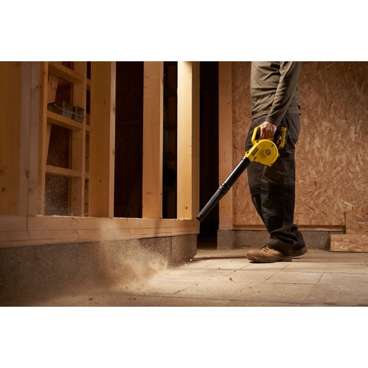 STANLEY SCBL01 blower in use cleaning construction site floor with yellow body and black nozzle.