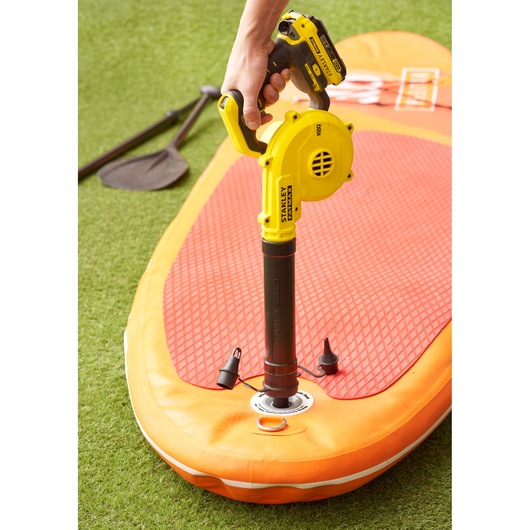 Stanley SCBL01 blower inflating orange paddle board, top angle view, paddle on grass background.