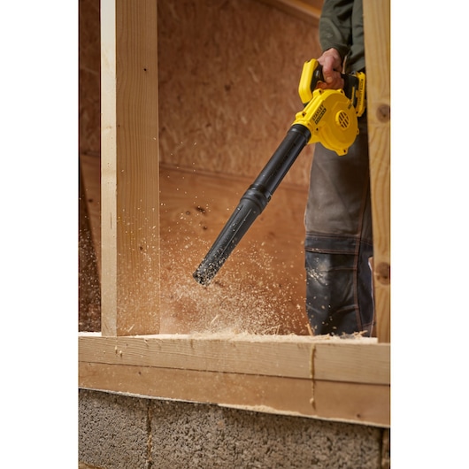 STANLEY SCBL01 blower in use clearing sawdust in a woodworking construction setting, side angle.