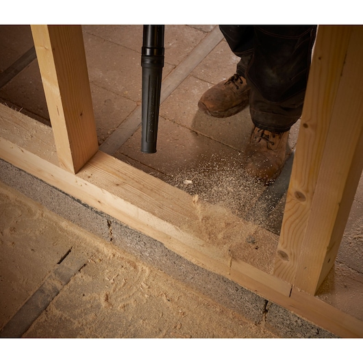 STANLEY SCBL01 vacuum nozzle cleaning sawdust from wooden framing on construction site, top down angle.