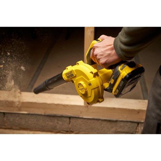Stanley SCBL01 yellow cordless blower used on wood surface, close-up angle.