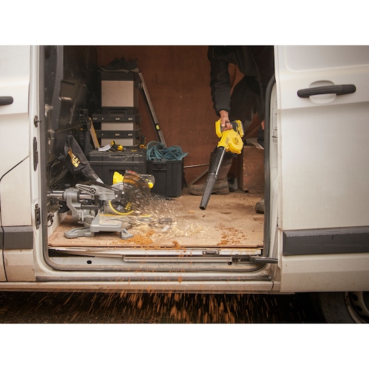 STANLEY SCBL01 blower in use inside work van with scattered wood shavings and power tools visible.