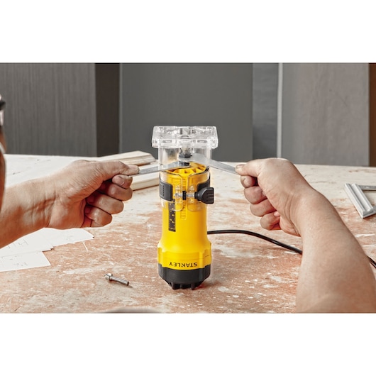 STANLEY ST55-KR yellow compact router being adjusted with tools on a workbench, photography front angle.