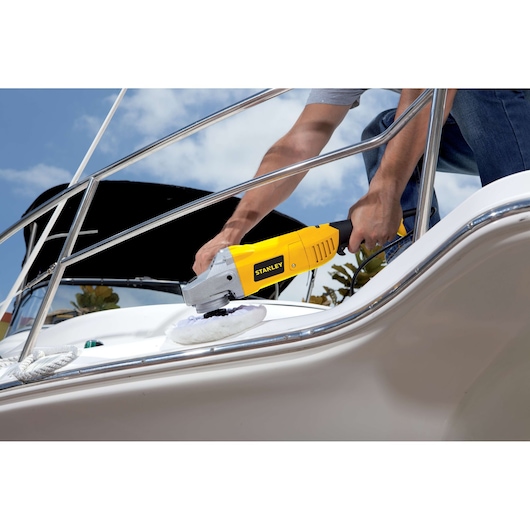 STANLEY STGP1318K polisher in use on a boat surface, handheld, outdoor setting.