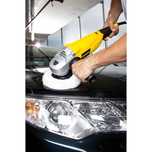 STANLEY STGP1318K polisher tool in use on a car hood, close-up photo showing yellow body and wool pad.