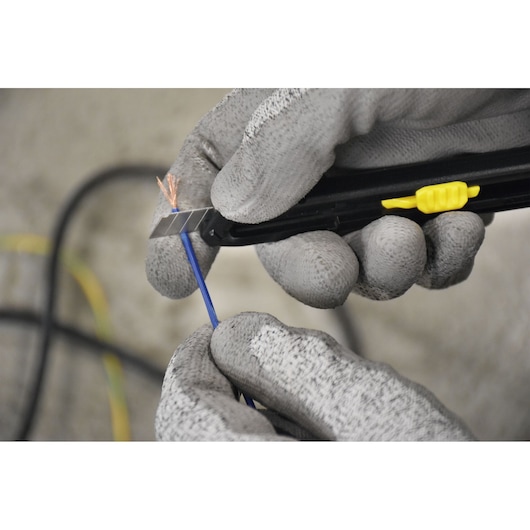 STANLEY STHT10322-840 utility knife cutting blue wire, close-up, with gloved hands, product category: Photography.