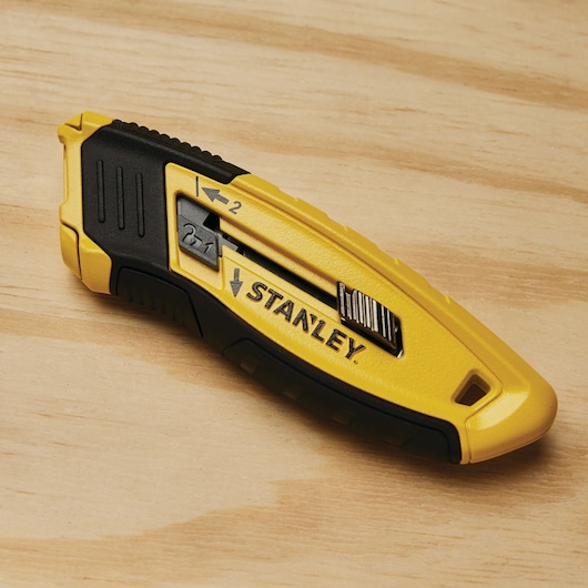 STANLEY STHT10432 yellow and black utility knife, side view, on wood surface.