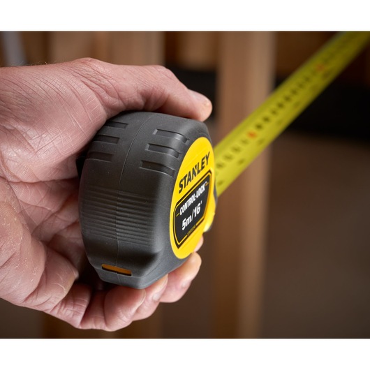 STANLEY STHT37246-0 tape measure with yellow blade held in hand, close-up photography.