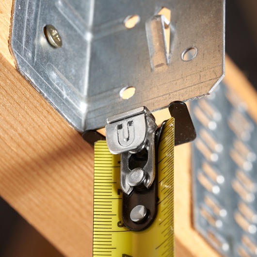 STANLEY STHT37247-0 tape measure close-up with yellow blade measuring metal bracket on wood.