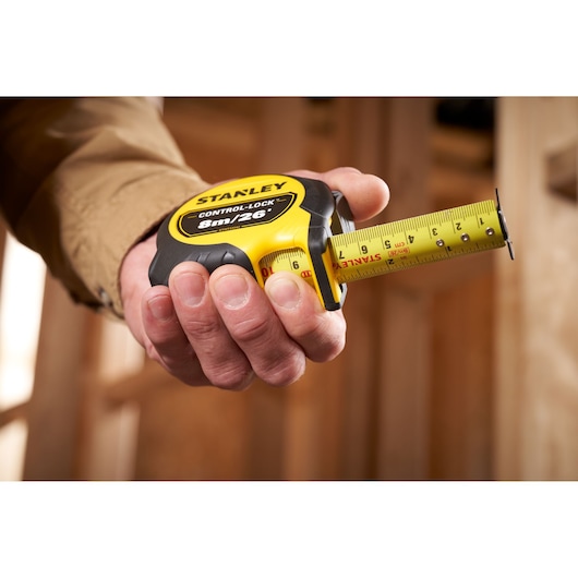 Stanley STHT37247-0 tape measure, yellow and black, shown held in hand, close-up photography.