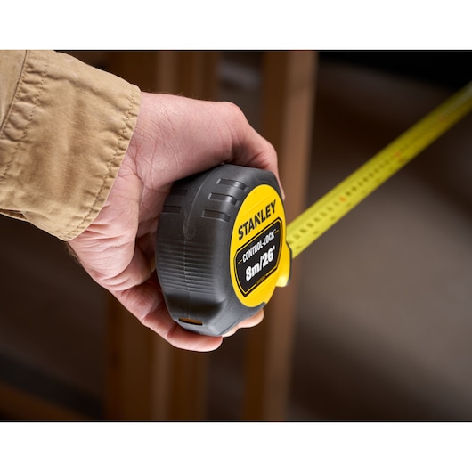 Stanley STHT37247-0 tape measure, yellow and black, held in hand, extended for measuring.