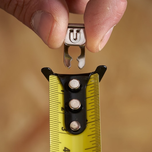 STANLEY STHT37247-0 tape measure tip with yellow blade and hand holding metal clip, close-up.