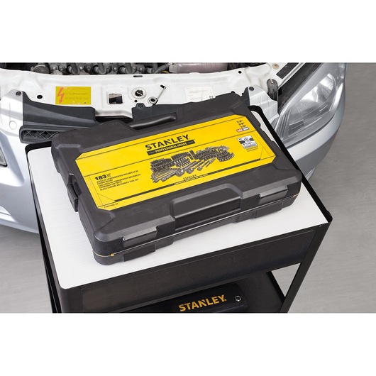 STANLEY STMT71662-LA tool set case with yellow label on a cart by a car, top angle.