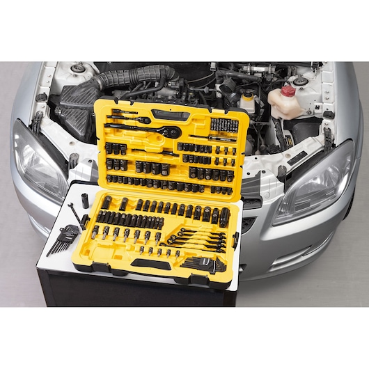 STANLEY STMT71662-LA yellow tool set with sockets and wrenches open in front of a car engine, top view.