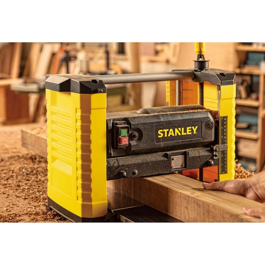 Stanley STP18-B2 planer in use, yellow and black, woodworking shop setting.