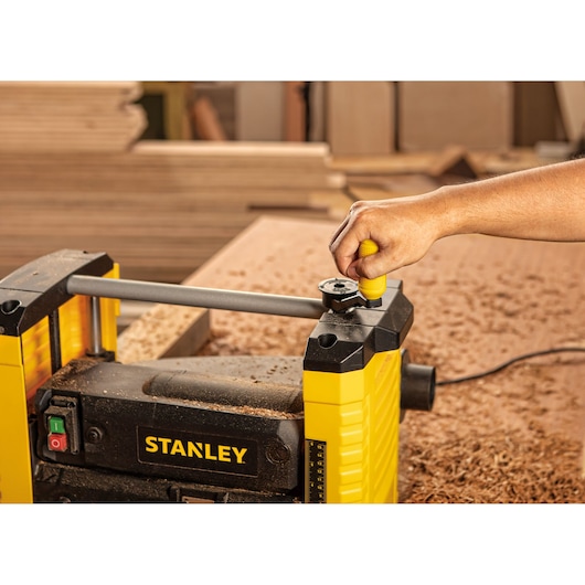 Stanley STP18-B2 woodworking planer with hand adjusting top knob in workshop setting.