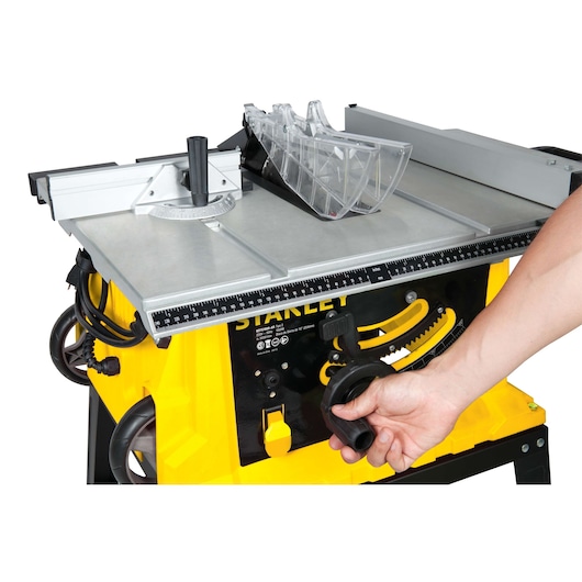 STANLEY STST1825 table saw side angle, showing yellow base, adjustment handle, and clear blade guard.