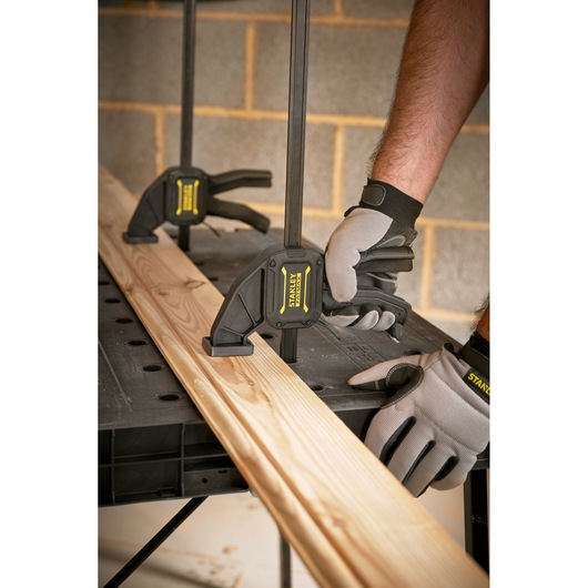 Stanley STST83492-1 photography of bar clamps securing wood on a workbench in workshop setting.