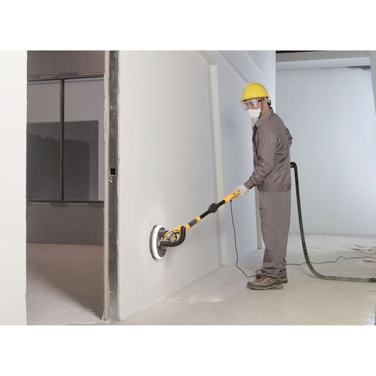 STANLEY SW75-BR drywall sander being used by a worker on a white wall, side photography.